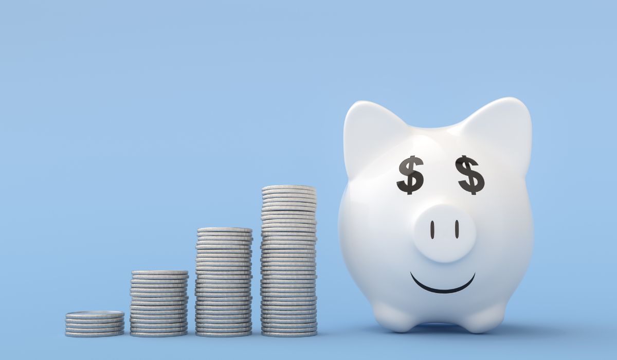 Una alcancía junto a montones de monedas sobre un fondo azul durante la Cuesta de enero.