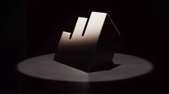 Un trofeo 3D estilizado con tres barras hacia arriba, que recuerda a los Effie Awards México 2024, se encuentra sobre un fondo oscuro, su superficie metálica brillantemente iluminada por un foco.