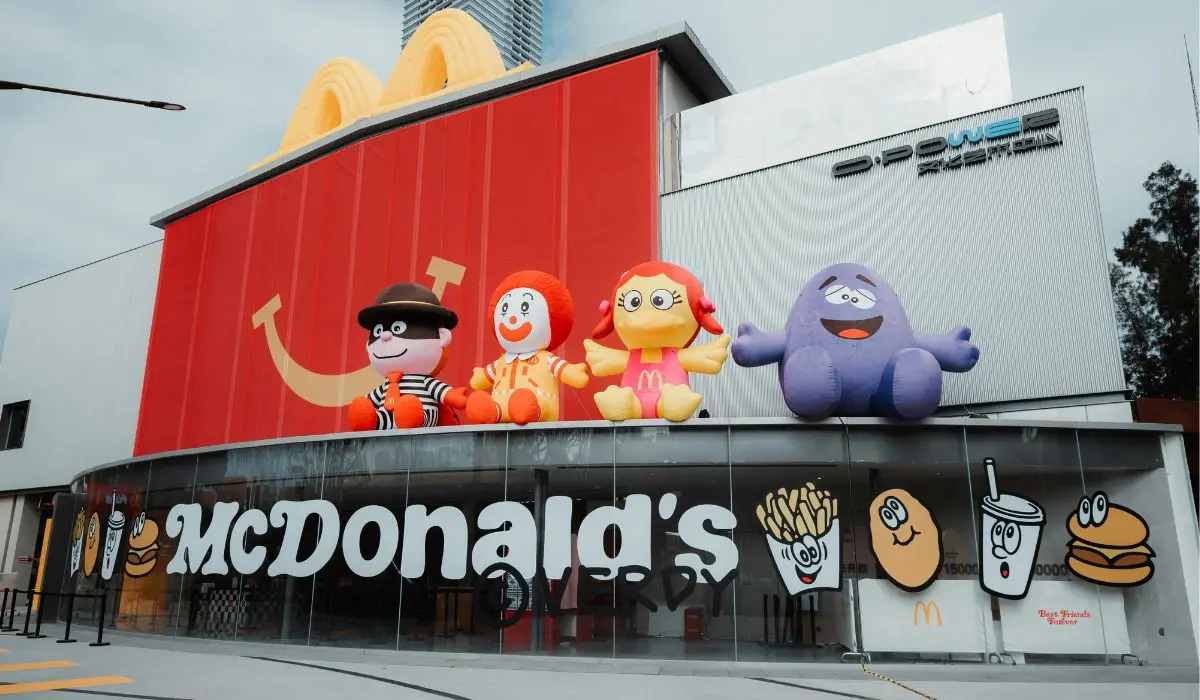 Vista frontal de un McDonald's con grandes personajes inflables en el techo e ilustraciones en las ventanas como publicidad exterior