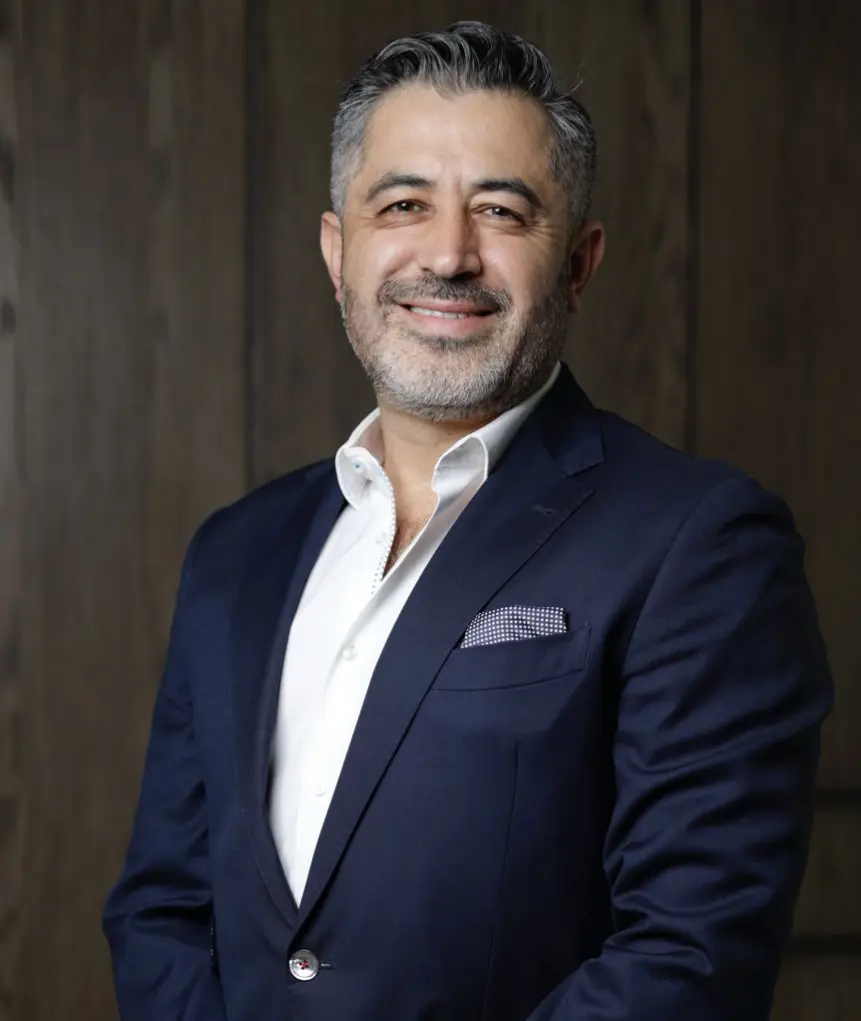 Un hombre de traje aparece sonriente frente a una pared de madera, encarnando el espíritu del Event Marketing 2025.