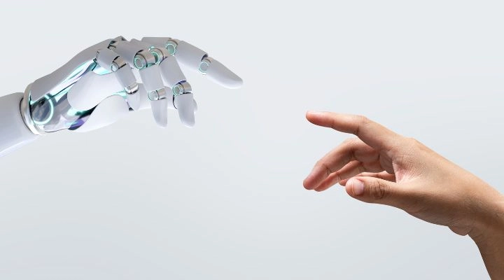 Una mano robótica y una mano humana se extienden una hacia la otra sobre un fondo liso, y las puntas de sus dedos casi se tocan, una escena que las agencias suelen explorar para simbolizar la intersección de la tecnología y la humanidad.